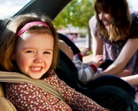 Little girl in car with mum in background