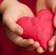child's hands holding playdough heart