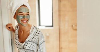 Woman smiles, wearing green face mask.