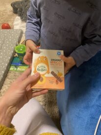 Child holding a box of little bellies snacks.