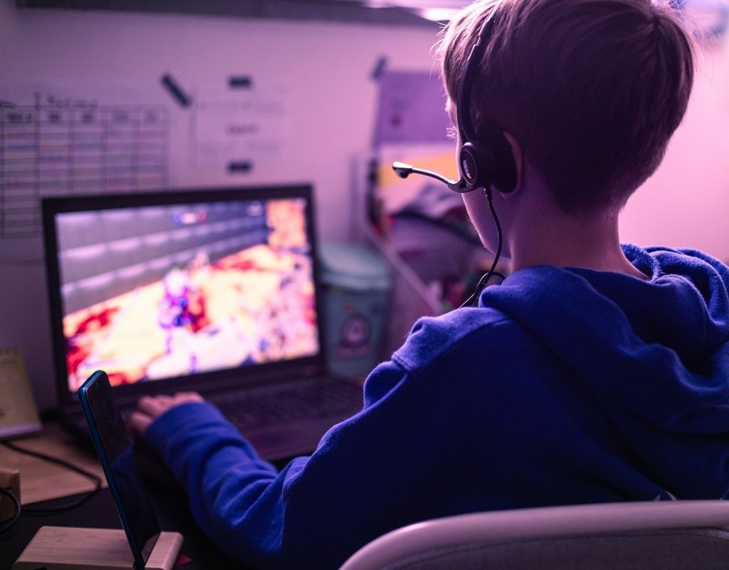Teenager sitting at the computer playing a video game.