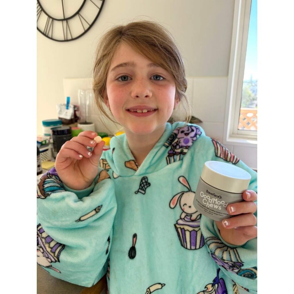 Child smiles at the camera holding the good mood chews tub.