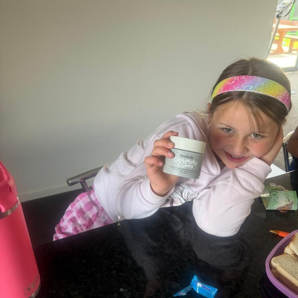Child smiles at the camera holding the good mood chews tub.
