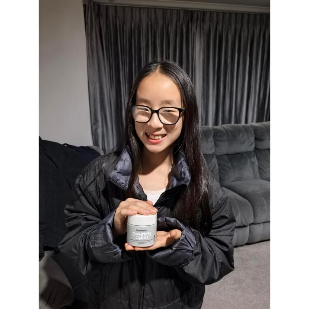 Child smiles at the camera holding the good mood chews tub.