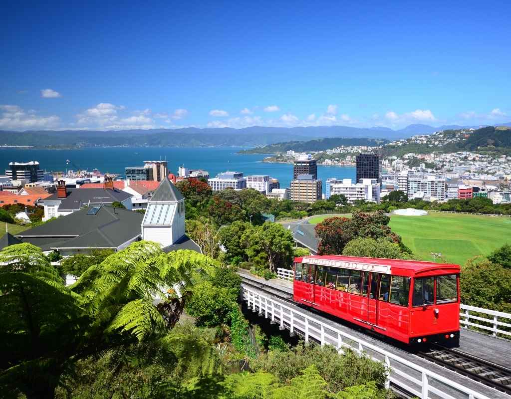 Photograph of the Wellington City red tram with the Wellington skyline in the back.
