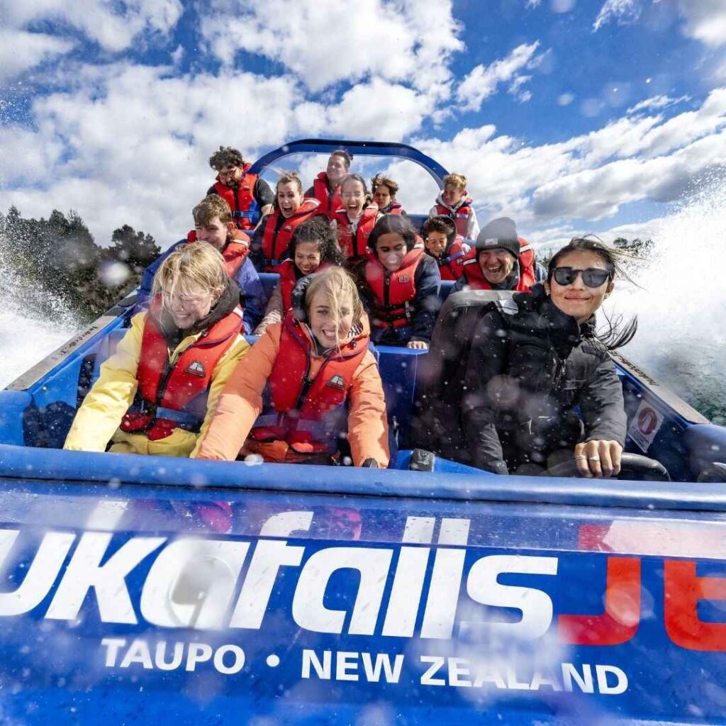 Group smile at the camera as they sit on a jet boat.