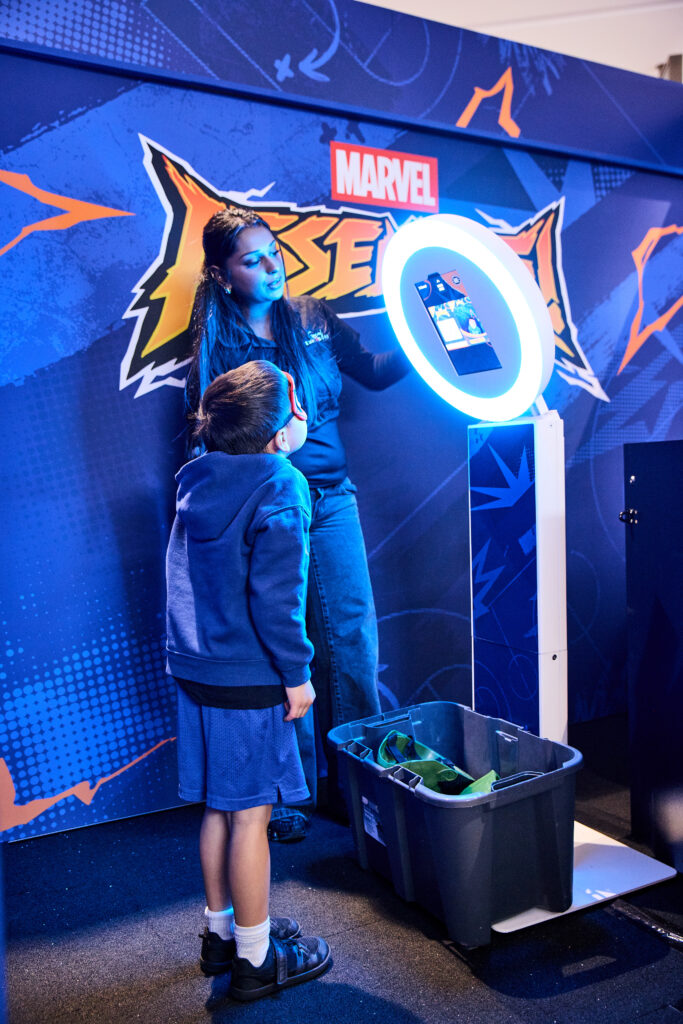 Young boy stands smiling at a photo booth.