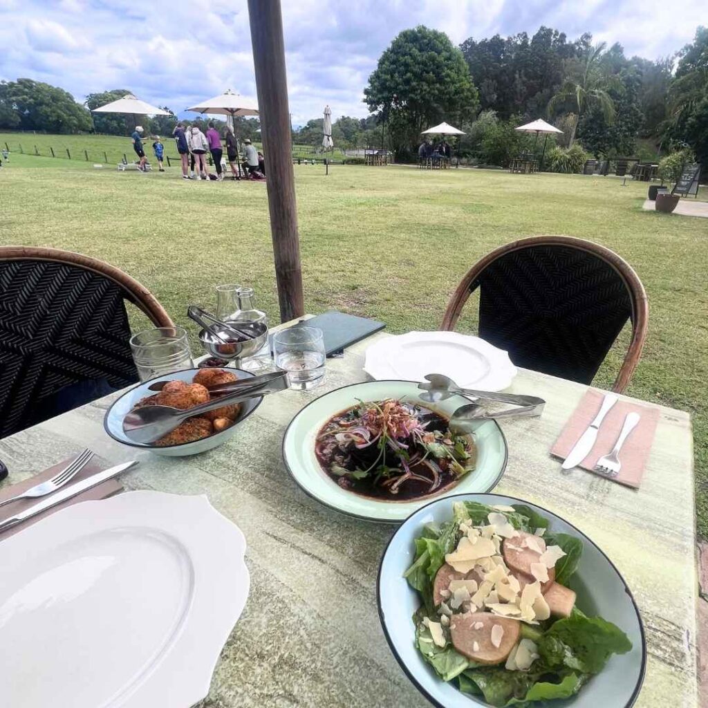 Three plates of food photographed in front of a sunny garden dining area.